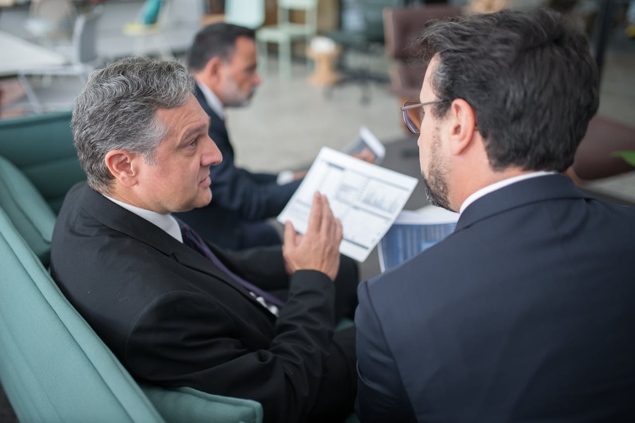 digital-01 Two businessmen engaged in a discussion, examining reports in a modern office environment.