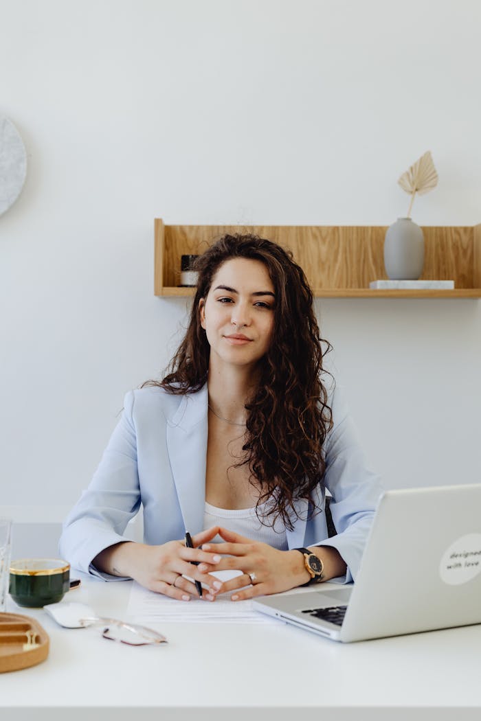 creative-03 Portrait of a confident businesswoman sitting at a desk with a laptop in a modern office.